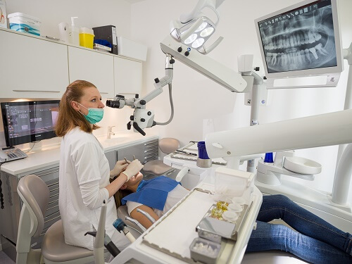 Zahnarzt bei der Wurzelkanalbehandlung mit dem OP-Mikroskop