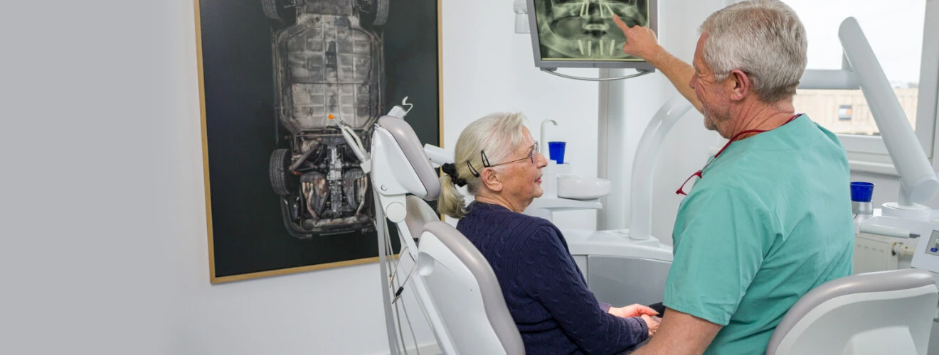 Zahnarzt zeigt Patientin All on 4 Lösung der Implantologie