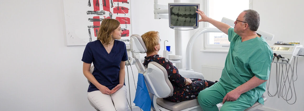 Zahnarzt zeigt Patientin Möglichkeiten von Zahnersatz