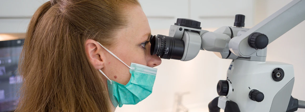 Zahnärztin am Mikroskop zur Wurzelbehandlung in Berlin