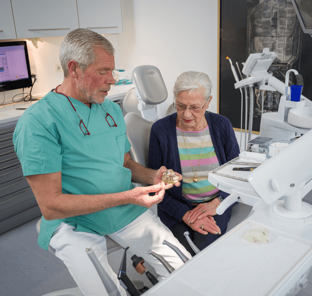 Zahnarzt Herr Hapke zeigt Patientin eine Teleskopprothese